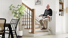Stairlifts homepage man and lady looking at book by stairs